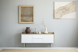 Front view of burlap artworks on a light gray wall above a woode